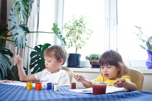 Kind tekent en kleurt de afbeelding met verf en een penseel