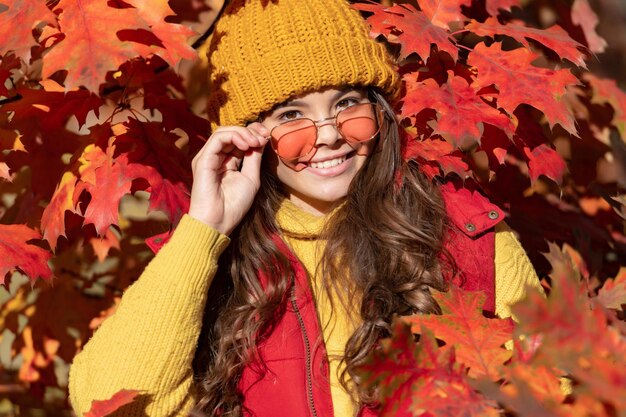Kind tiener meisje in herfst herfst park buiten herfst plezier kinderen gezicht vrolijke tiener meisje in zonnebril op herfstbladeren op natuurlijke achtergrond