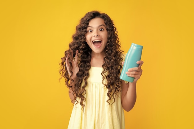 Foto kind tiener meisje met shampoos, conditioners en douchegel lange haarverzorging van tiener cosmetisch product shampoofles presenteren opgewonden tiener blij verbaasd en dolblij emoties