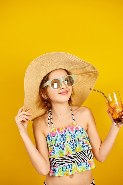 Kind tienermeisje in badpak strohoed en zonnebril met limonade