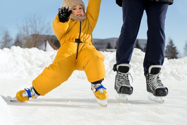 Kind valt bij de eerste poging om op te staan op schaatsen en houdt vaders hand vast