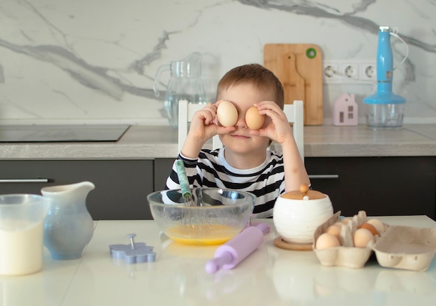 Kind van 56 leert koekjes koken in de witte keuken Gelukkige kind kookt deeg bakt koekjes Kinderen leren nieuwe dingen Concept van kinderafstand