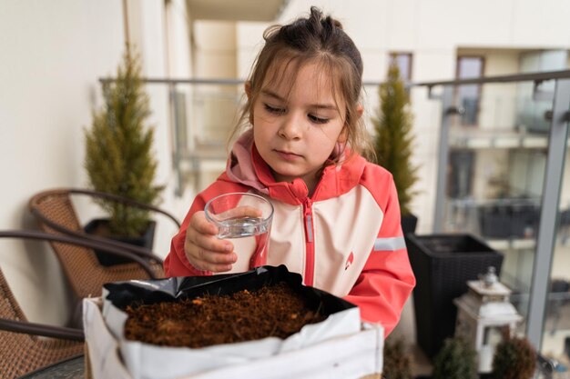 Foto kind van voorschoolse leeftijd meisje zaait planten op het balkon stedelijke tuinieren duurzaam onderwijs