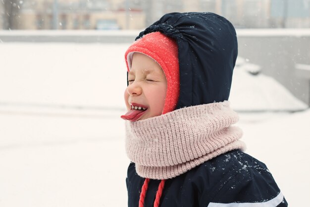 Kind vangt de sneeuw met zijn mond