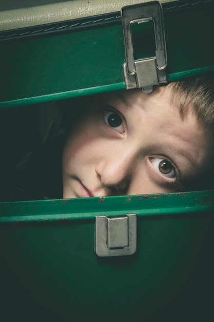 Kind verstopt zich in een oude groene koffer