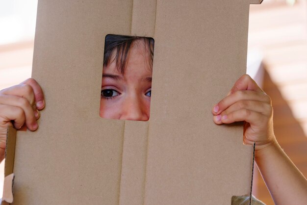 Foto kind verstopt zich in karton waar alleen een deel van het gezicht zichtbaar is