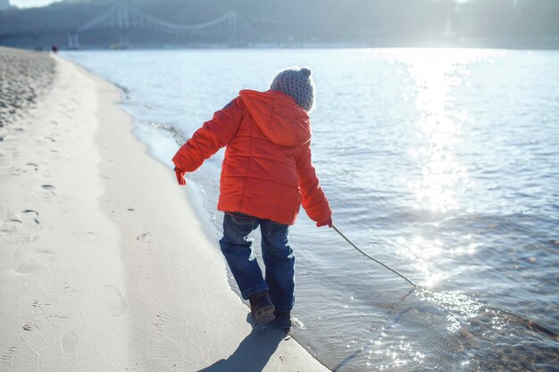 Kind wandelen langs de oever van de rivier en genieten van zonnige winterdag