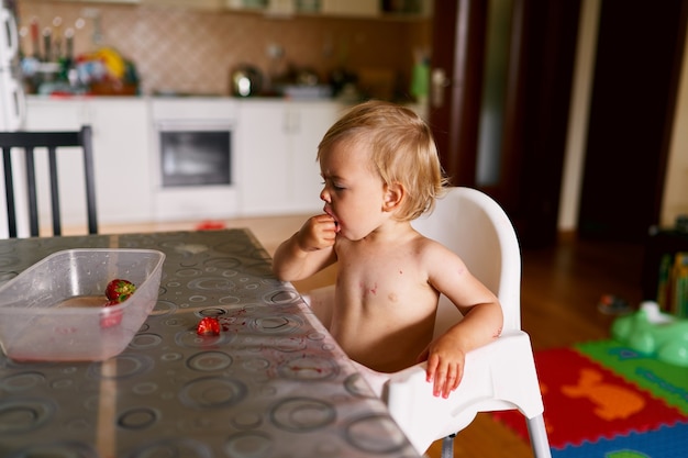 Kind zit aan tafel en eet aardbeien