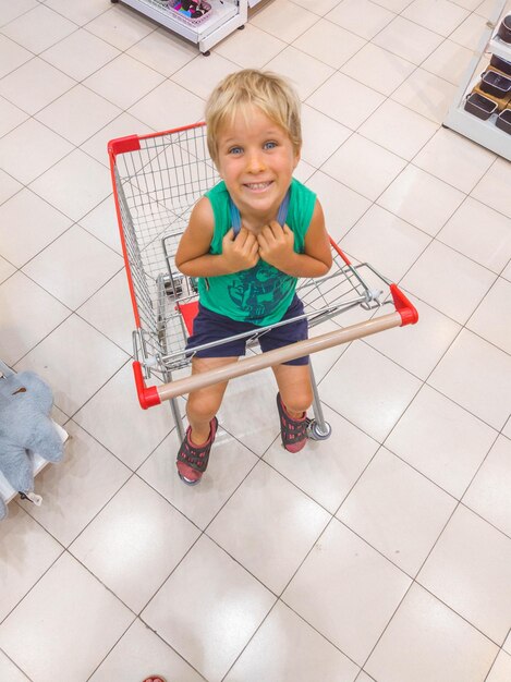 Kind zit in een winkelmandje in de supermarkt en vraagt om nieuw speelgoed te kopen met een kinderconcept