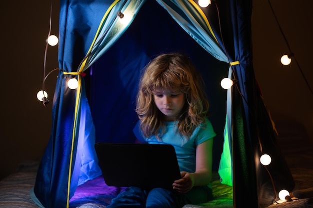 Kind zit in huistent te spelen met laptop Sociale media voor kinderen