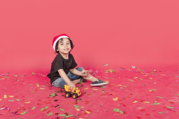 kind zit te spelen met een gele vrachtwagen met een roze vloer vol confetti geïsoleerde foto