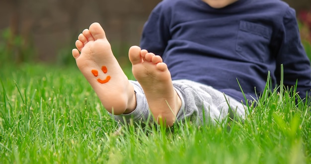 Kind zittend op het gras, glimlachend op het been van het kind met verf