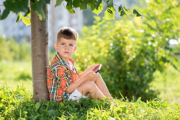 kind zittend op het gras kijken op de telefoon