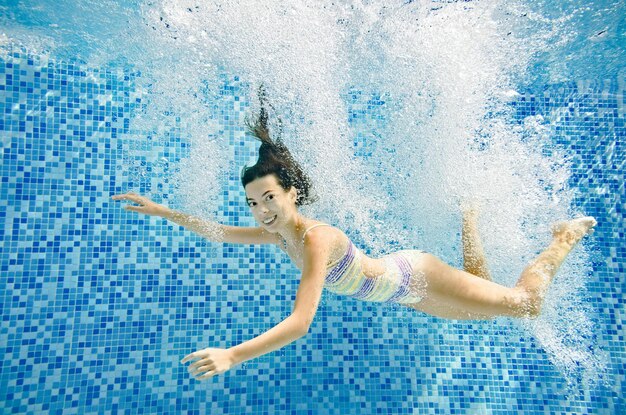 Foto kind zwemt onder water in zwembad actief klein meisje springt duikt en heeft plezier onder water