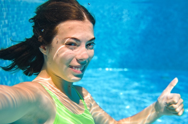 Kind zwemt onder water in zwembad gelukkig actief tienermeisje duikt en heeft plezier onder water