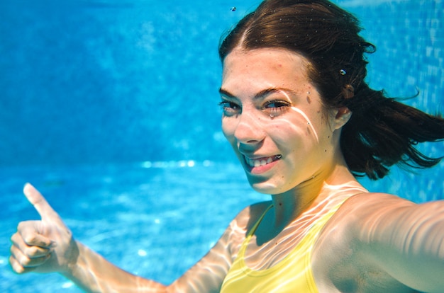 Kind zwemt onder water in zwembad, gelukkig actieve tiener meisje duikt en heeft plezier onder water, kid fitness en sport op familievakantie op resort