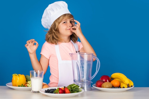 Kindchef-kok geïsoleerd op blauwe grappige kleine chef-kok met uniforme koksmuts en schort gekookt foo