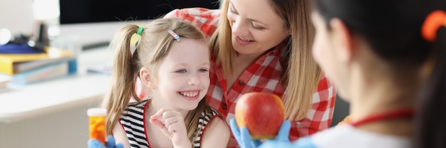 Kinderarts arts die moeder en kind appel of medicijnpot aanbiedt