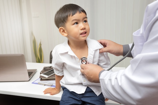 Kinderarts diagnosticeert een kleine patiënt met behulp van een stethoscoop