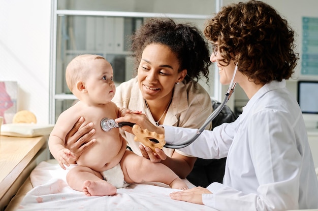 Foto kinderarts luistert naar baby met stethoscoop tijdens medisch onderzoek in het ziekenhuis