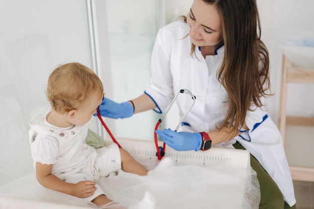 Kinderarts luistert naar de hartslag van baby's met een stethoscoop tijdens controle thuis