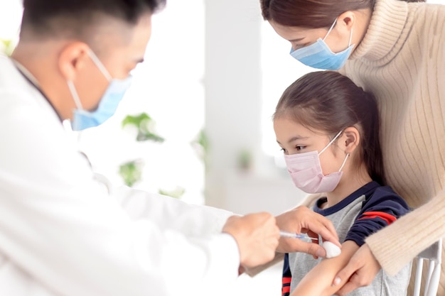 Kinderarts onderzoekt kind en geeft injectie Coronavirusvaccinatie en Covid19-vaccinconcept