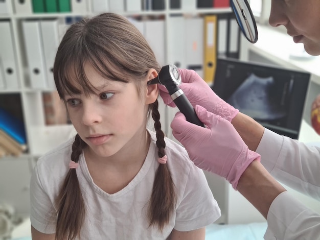 Kinderarts onderzoekt kleine patiënt met een otoscoop controleert het gehoor van kinderen