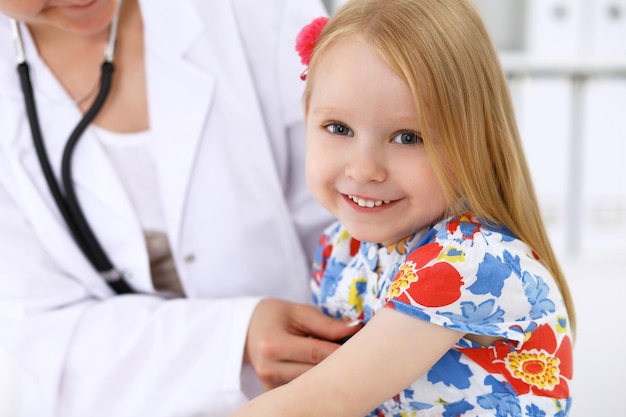 Foto kinderarts zorgt voor baby in het ziekenhuis klein meisje wordt door een arts onderzocht met een stethoscoop gezondheidszorgverzekering en hulpconcept