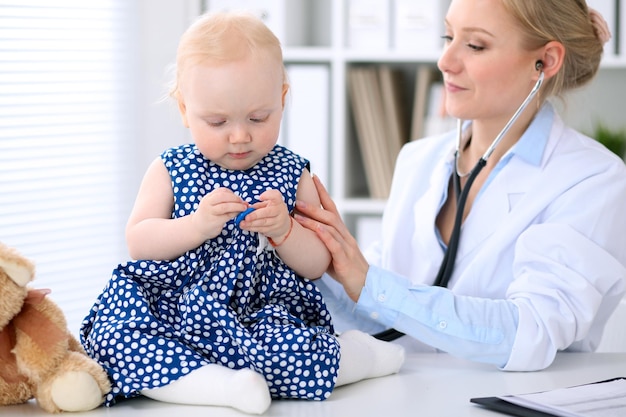 Kinderarts zorgt voor baby in het ziekenhuis. klein meisje wordt onderzocht door een arts met een stethoscoop. gezondheidszorg, verzekering en hulpconcept.