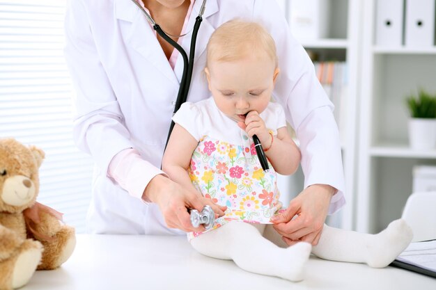 Kinderarts zorgt voor baby in het ziekenhuis. Klein meisje wordt onderzocht door een arts met een stethoscoop. Gezondheidszorg, verzekering en hulpconcept.