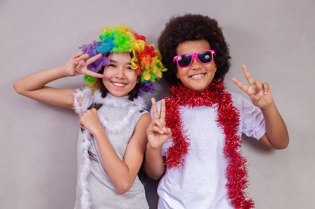 Foto kinderdagconcept. twee kinderen, een afrojongen en een aziatisch meisje in kleurrijke kleren die feesten