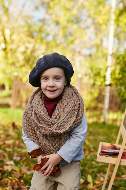 Kinderen baby in retro herfst lente kleding. Klein kind zit glimlachend in de natuur, sjaal om zijn nek, koel weer