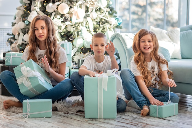 Kinderen bij de kerstboom die cadeautjes opent op kerstochtend.