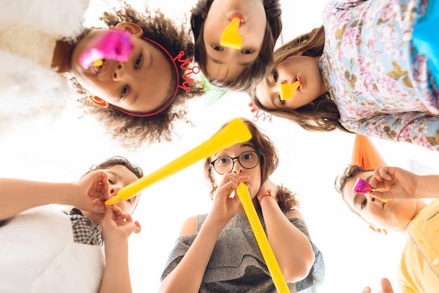 Kinderen blazen op feestelijke pijpen op verjaardagsfeestje