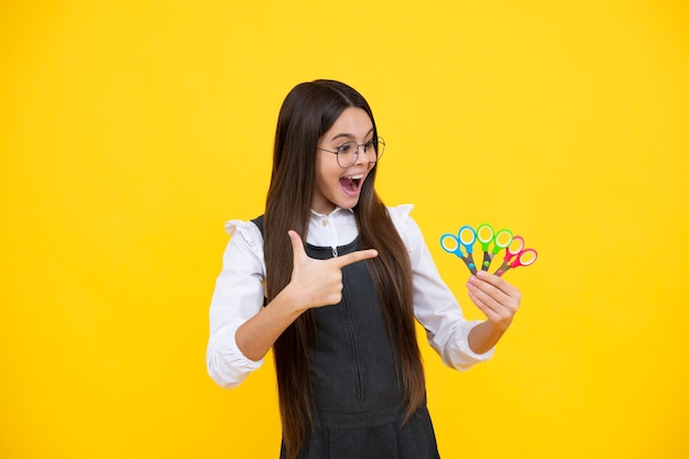 Kinderen creativiteit kunsten en ambachten tienermeisje met schaar geïsoleerd op gele achtergrond