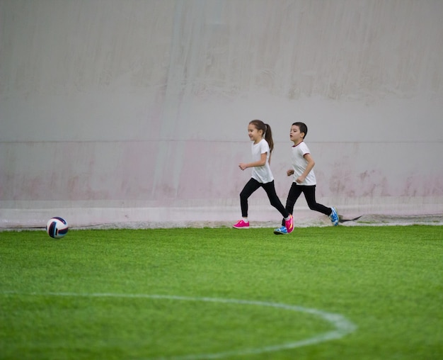 Kinderen die binnen voetbal spelen een klein meisje en een jongen spelen