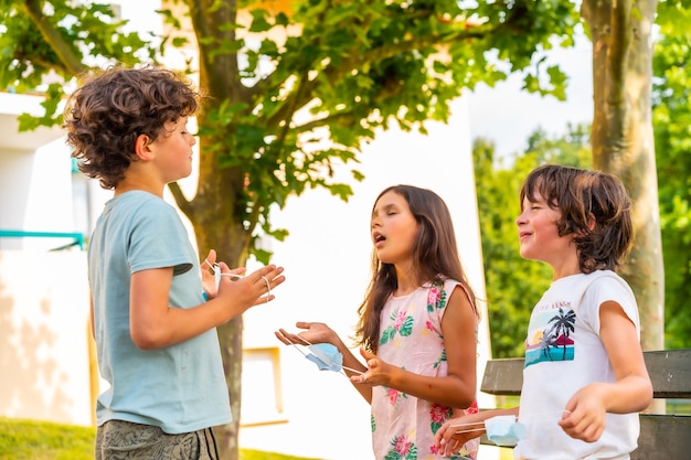 Kinderen die buiten op een bankje zitten en hun mondkapje afzetten