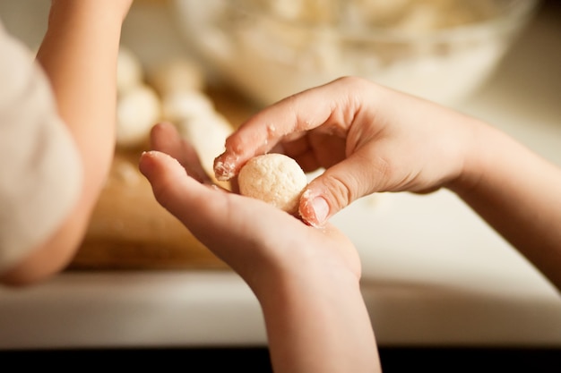 Kinderen die een russische syrniki van kwarkballen maken in de huiskeuken.