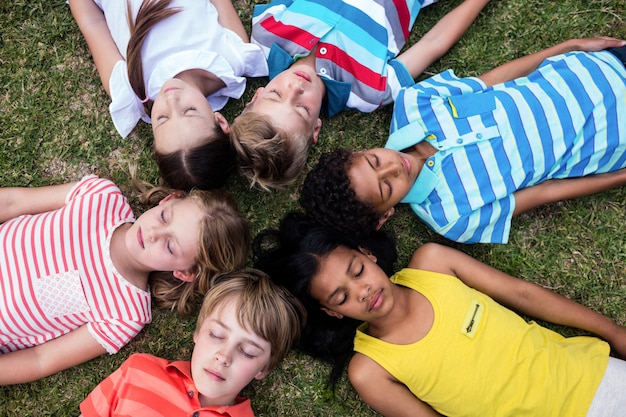 Kinderen die op gras met gesloten ogen liggen