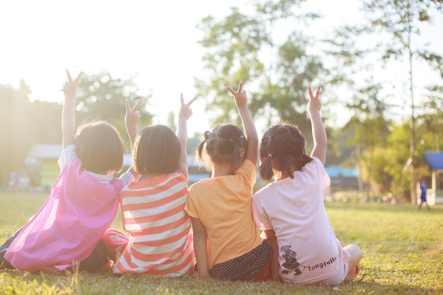 Kinderen die op groen gras in het park zitten.