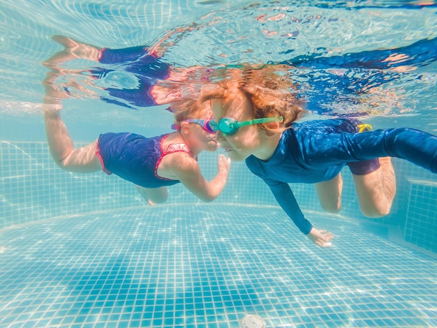 Kinderen die plezier hebben met onderwater spelen in het zwembad op zomervakantie