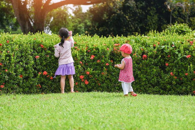 Kinderen die pret spelen die buiten Aziatisch jonge geitjesmeisje gelukkig in het tuinpark hebben met bloemboom