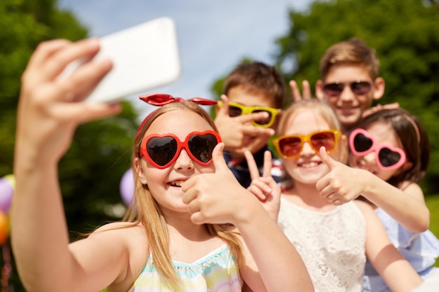 Kinderen die selfie's maken en hun duim omhoog laten zien in het park.