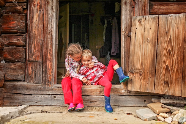 Kinderen die tijdens de zomervakantie voor de deur van een oud houten huis rusten, milieuvriendelijk reisconcept