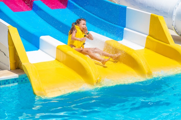 Kinderen die van de glijbanen in een waterpark naar beneden glijden