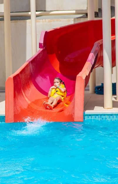 Kinderen die van de glijbanen in een waterpark naar beneden glijden