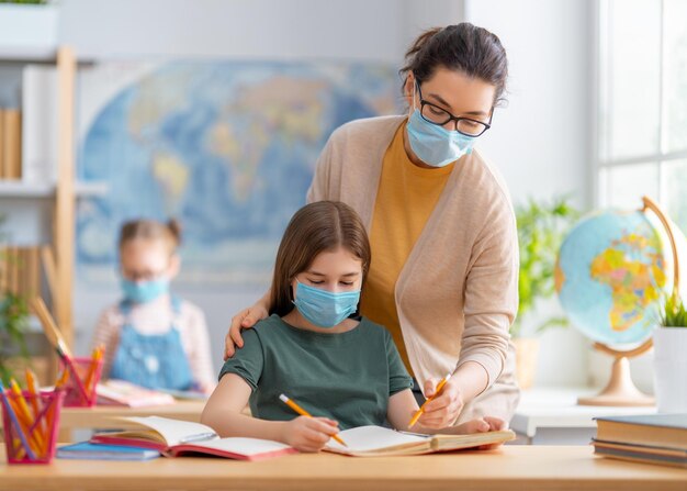 Kinderen dragen gezichtsmaskers die in de klas leren