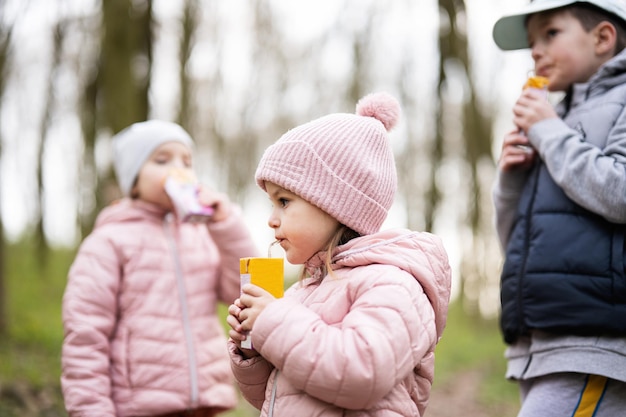 Kinderen drinken sap met rietjes op gelukkige kindermomenten in het bos