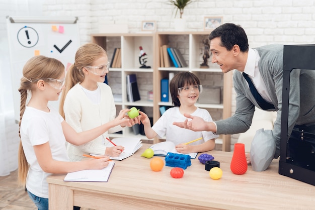 Kinderen drukken verschillende items op 3D-printer met een leraar.