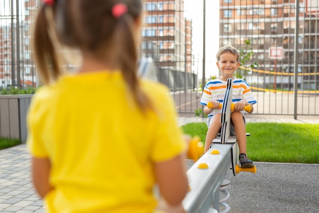 Kinderen een jongen en een meisje hebben plezier op een schommel in de frisse lucht Plezier in het park